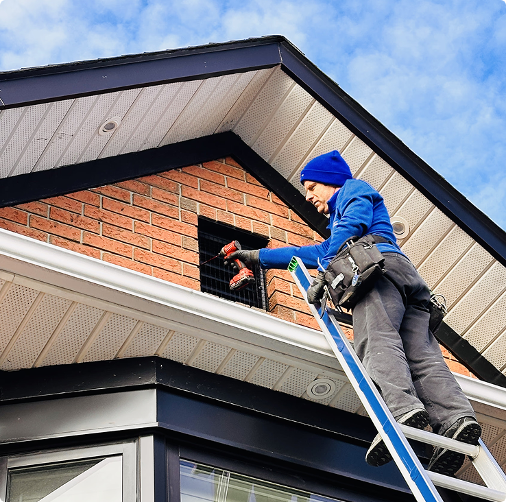 Technician installing wildlife exclusion at a roofline vent